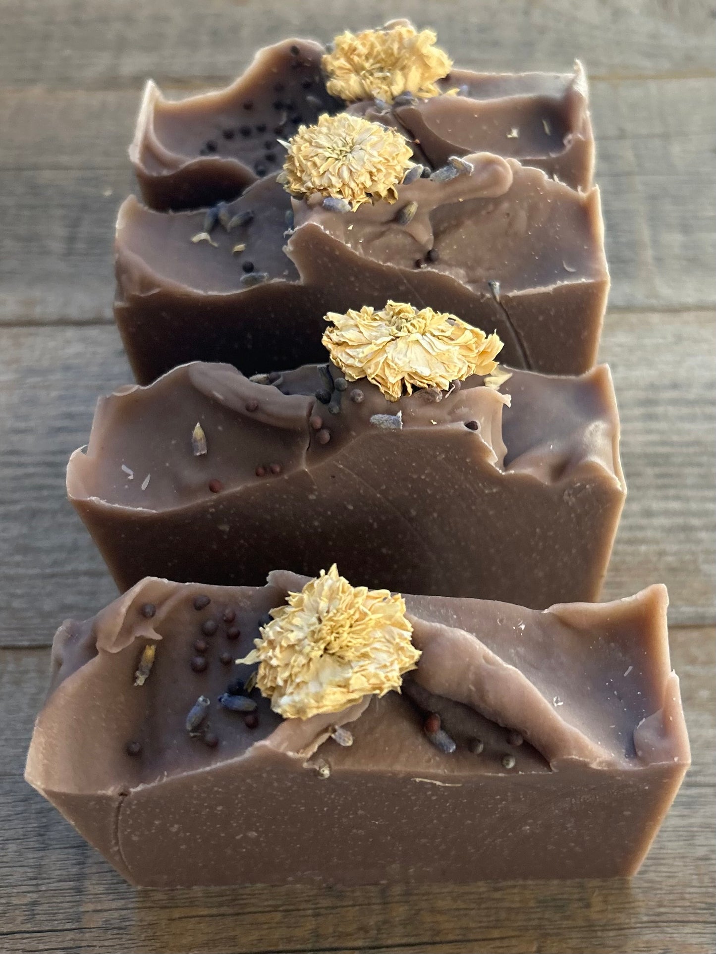 Take a step into the country with Wild Lavender soap. Scented with lavender, patchouli and juniper essential oil and sandalwood powder. It's the perfect blend of rich earthy floral. Made with nourishing goat's milk, olive oil, coconut oil, cocoa butter, avocado oil and castor oil. This soap is naturally colored with purple Brazilian clay and sandalwood powder for light exfoliation. Topped with lavender buds, broccoli seeds and a white chrysanthemum. Kendrick Homestead